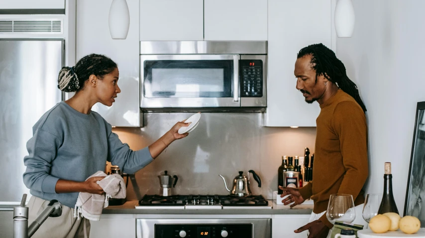 two people in the kitchen one holding a piece of paper