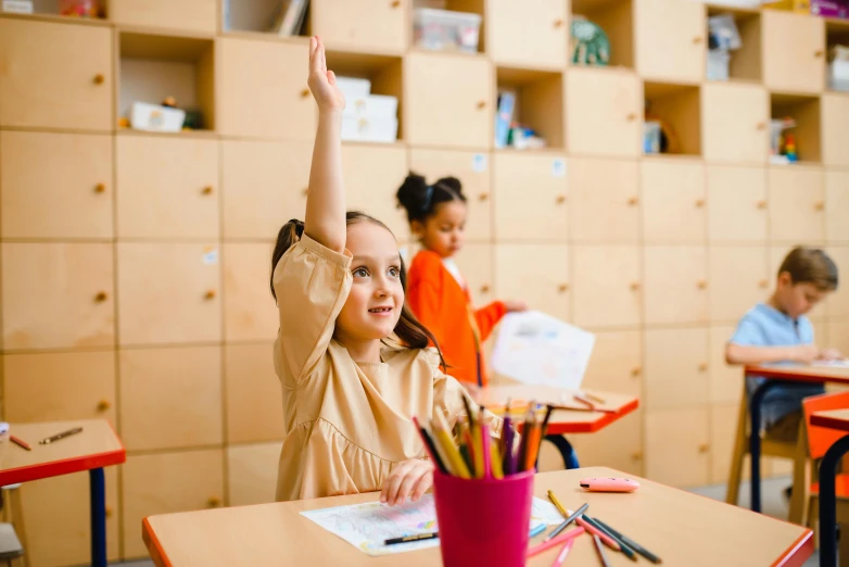 two girls and one boy with their hands up in front of them in a school