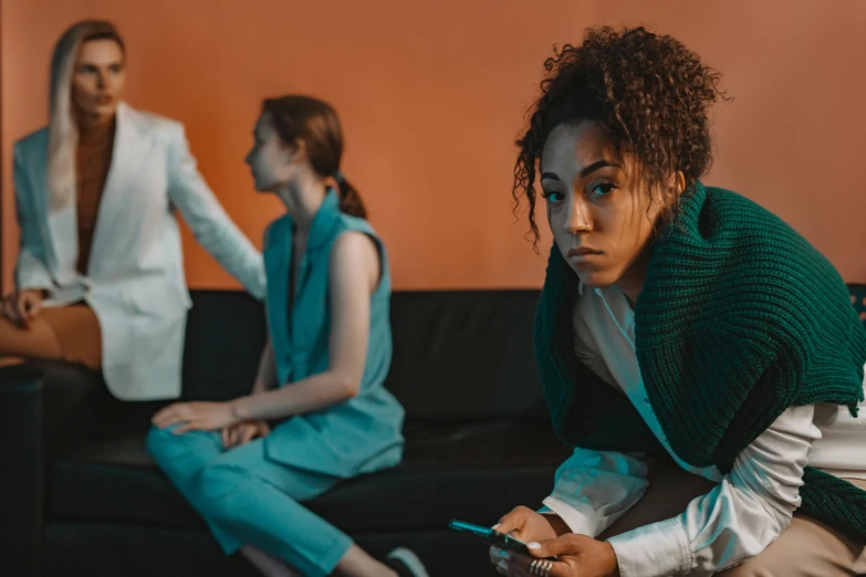 two women sitting on a couch looking at their phones