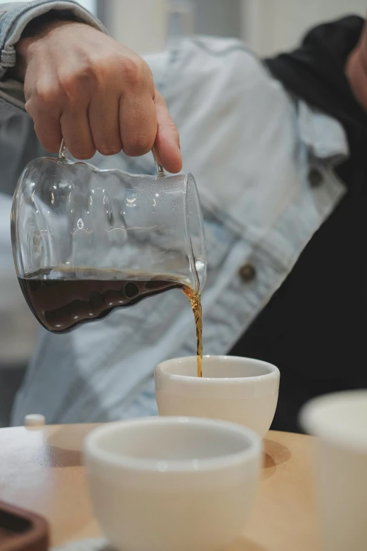 man pouring syrup over a cup sitting on the table