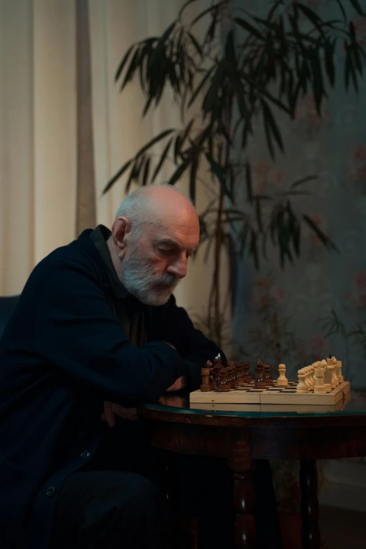 an old man sits at a table with a chess set