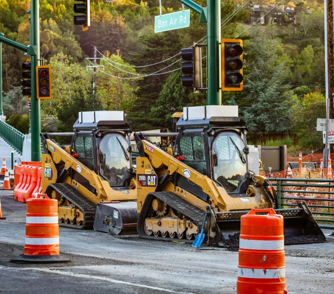 construction equipment is seen behind construction cones on a street