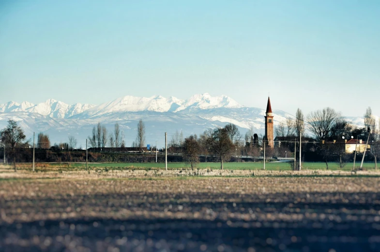 a church tower with a tower spire stands in front of a mountainous landscape