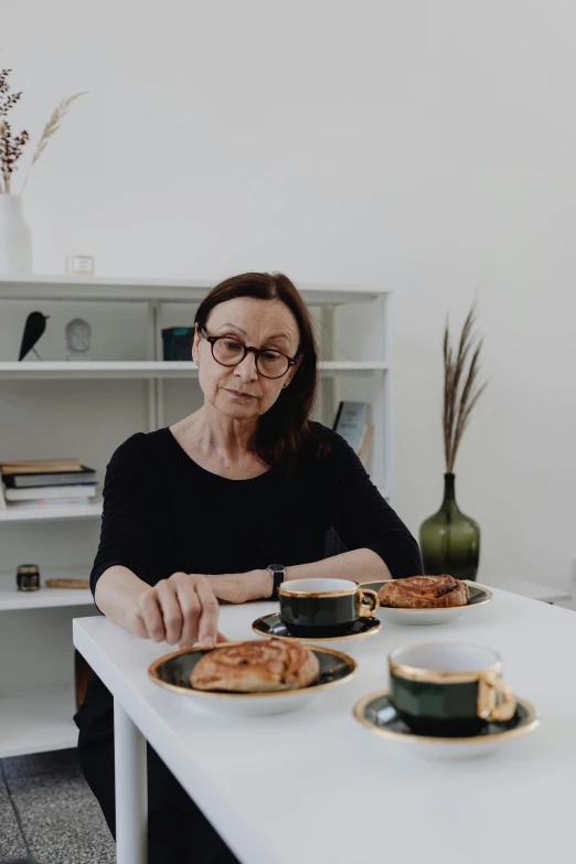 a woman sitting at a table with two cups of coffee