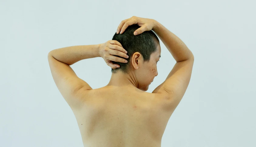 a shirtless man scratching his hair