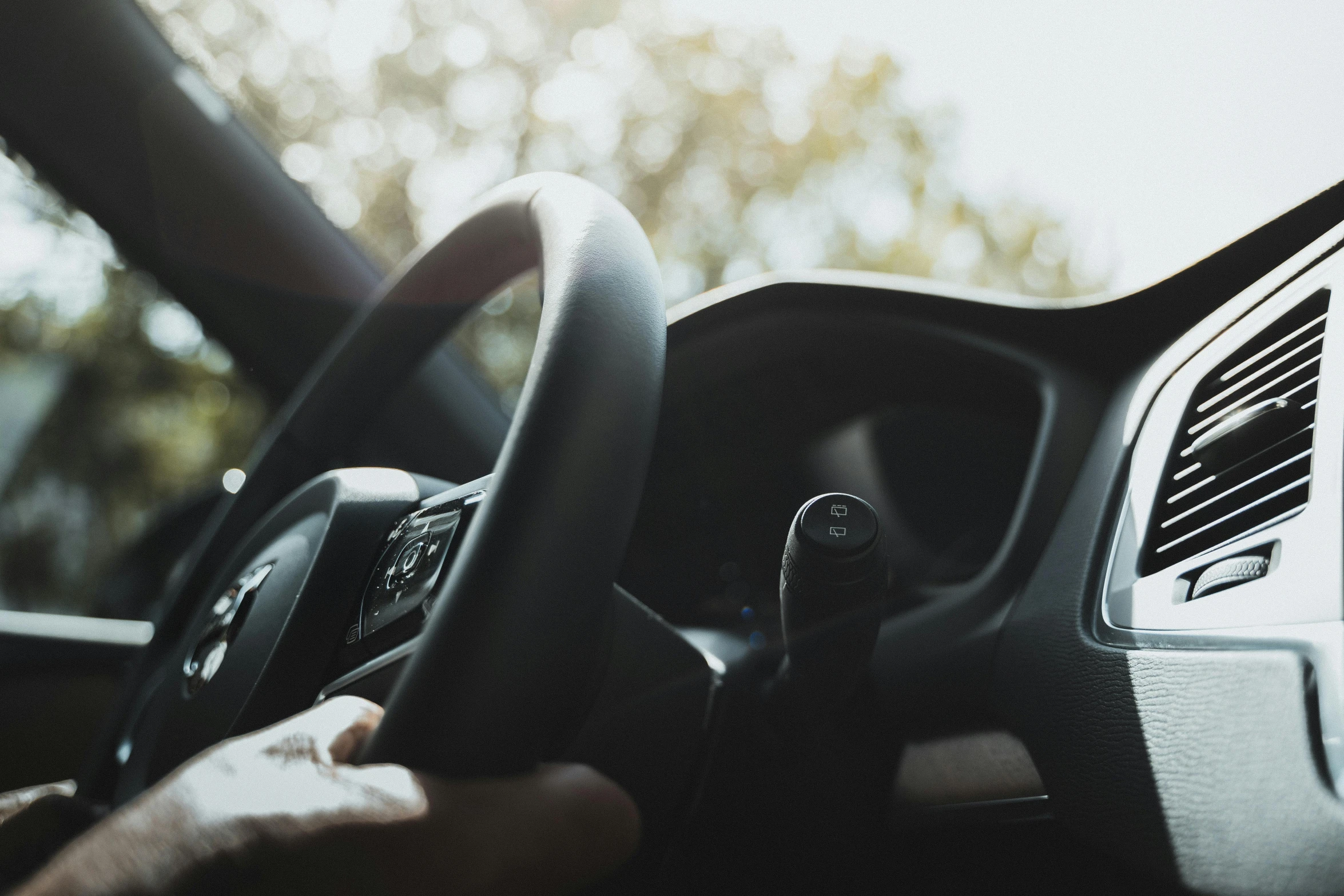 a person is driving their car while holding the steering wheel