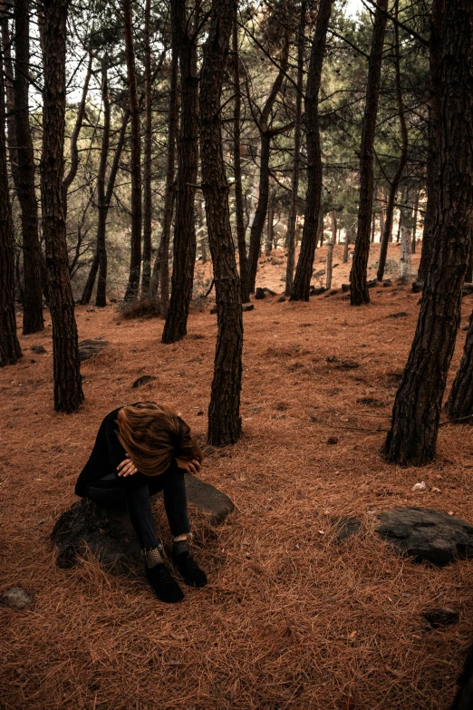 a young man kneeling on top of a grass covered forest