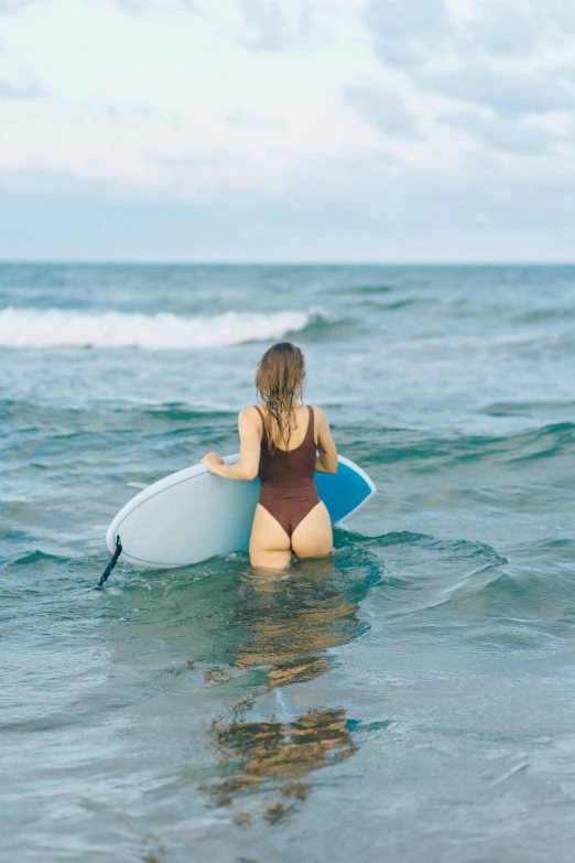 a woman in a swimsuit holding a surfboard while walking out of the ocean