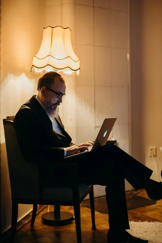 a man sits in a chair while using a laptop