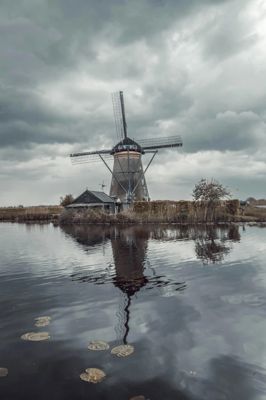 an old windmill is sitting in the middle of the water