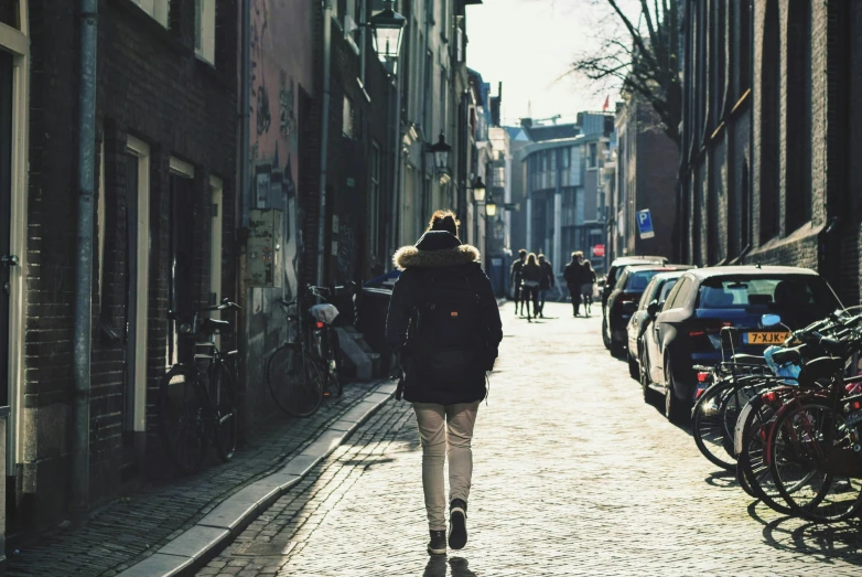 a person walks down a sidewalk with cars parked on it