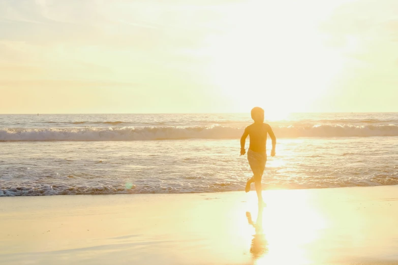 a man in swimming trunks running along the beach towards the ocean