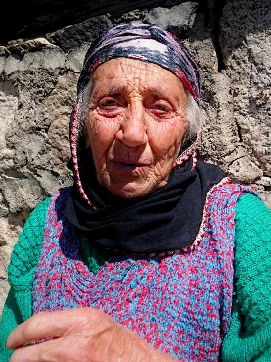 an old woman is sitting on a rocky ground