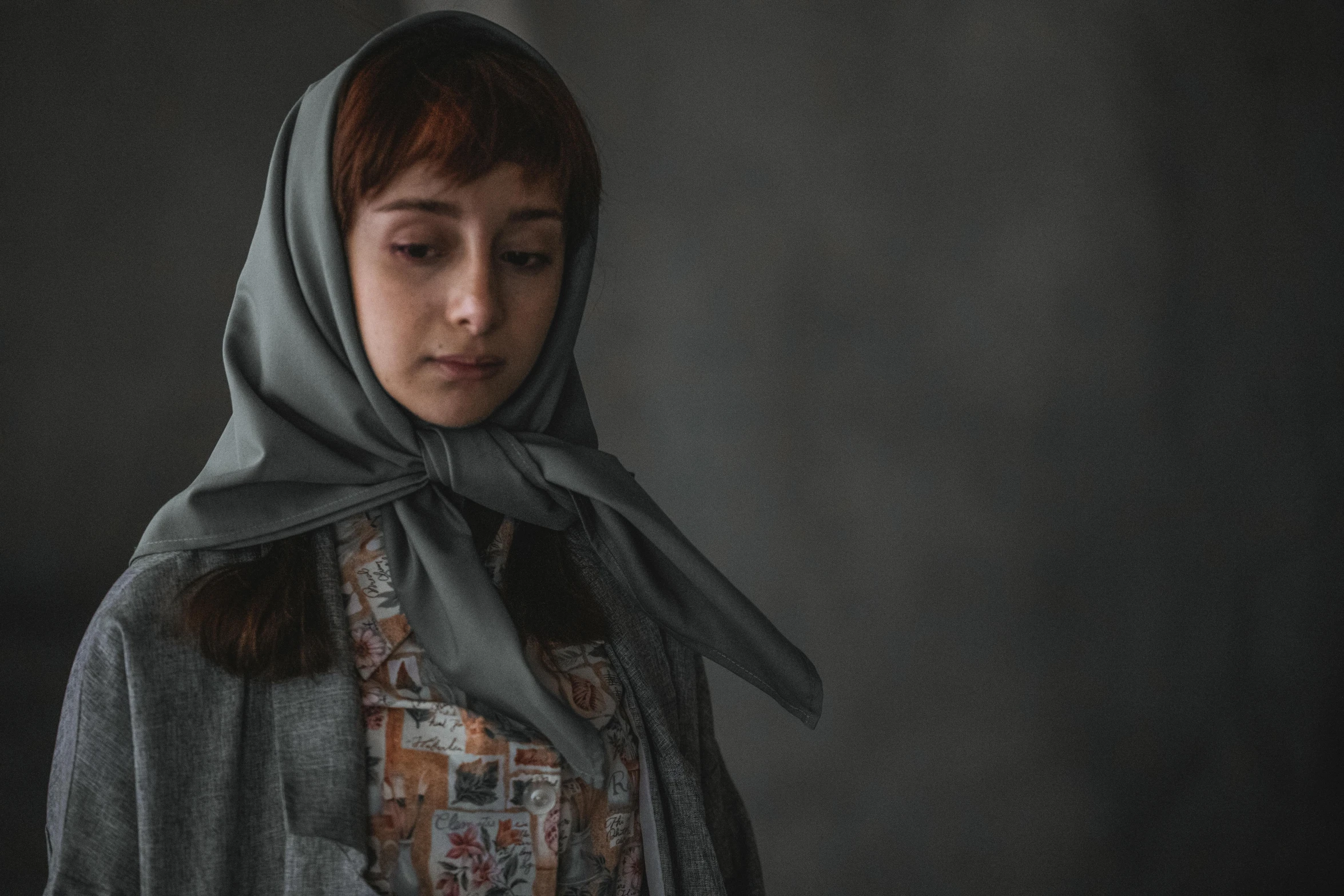 a woman is wearing a shawl in a dark room