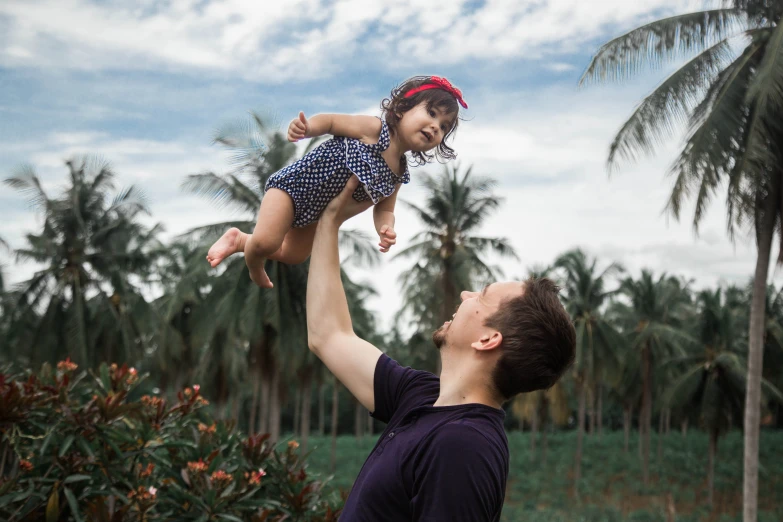 a father lifting up his little girl to catch a frisbee