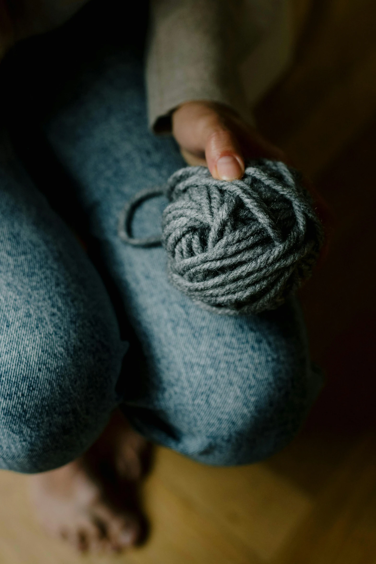 a person wearing blue pants holding yarn ball in their hand