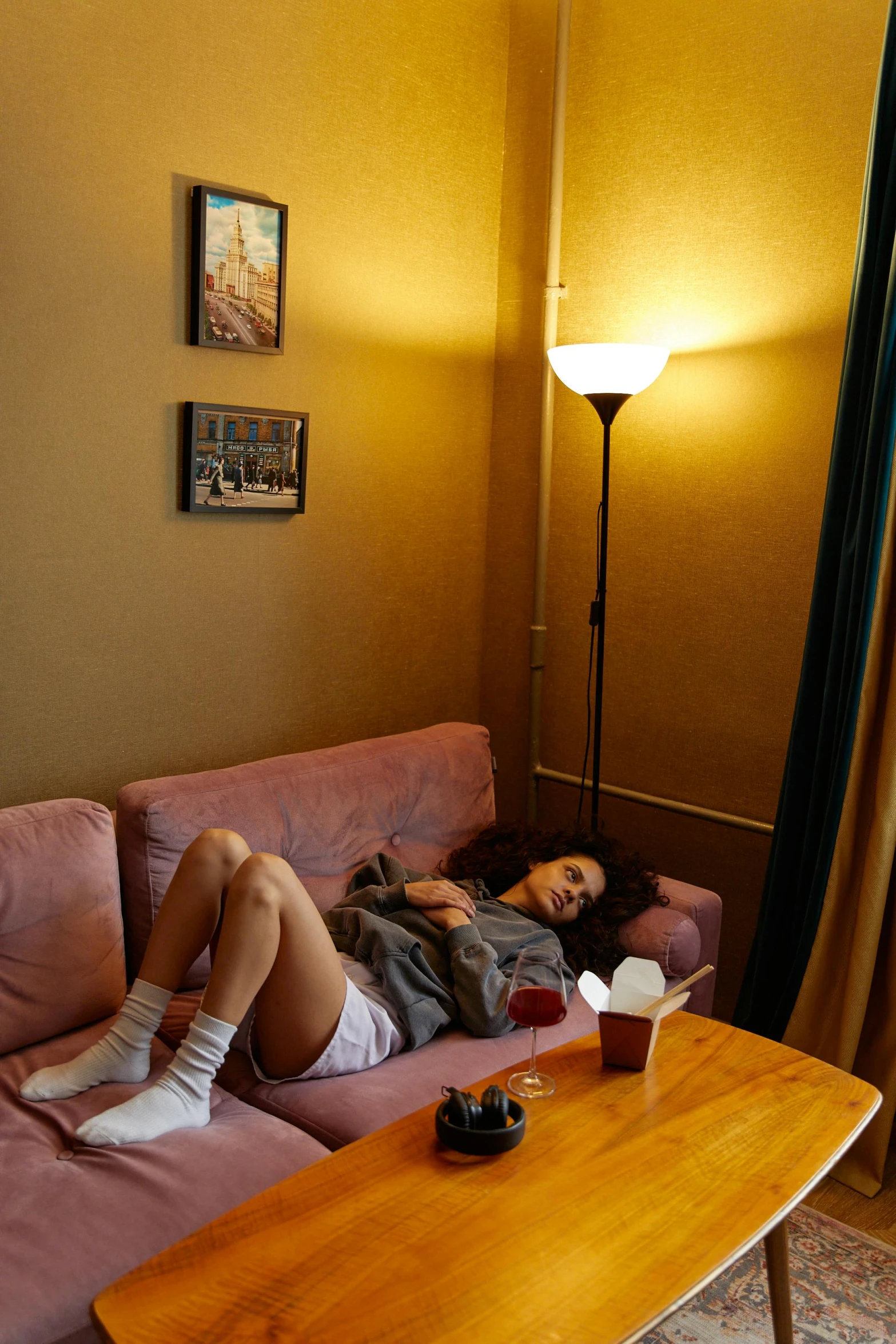 a woman lies on a pink couch in a living room