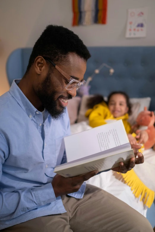 a man sitting on top of a bed holding a book