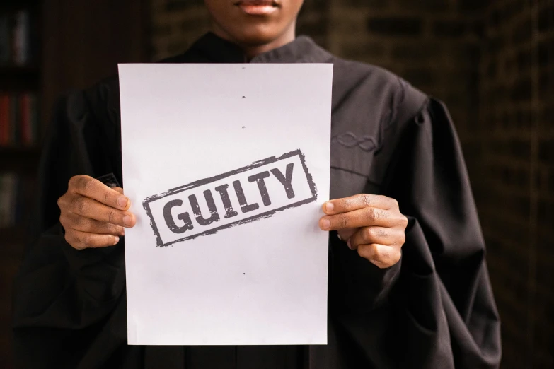 a person holding up a paper with the word guilt written on it