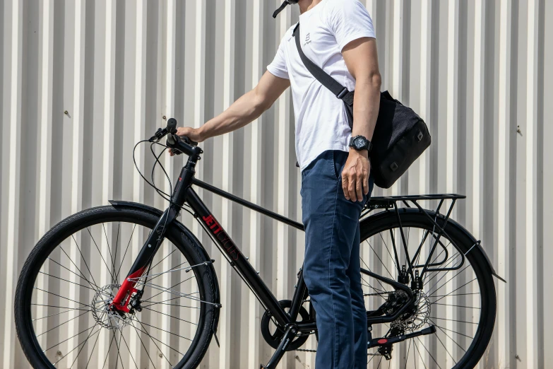 a man holding his bicycle next to a building