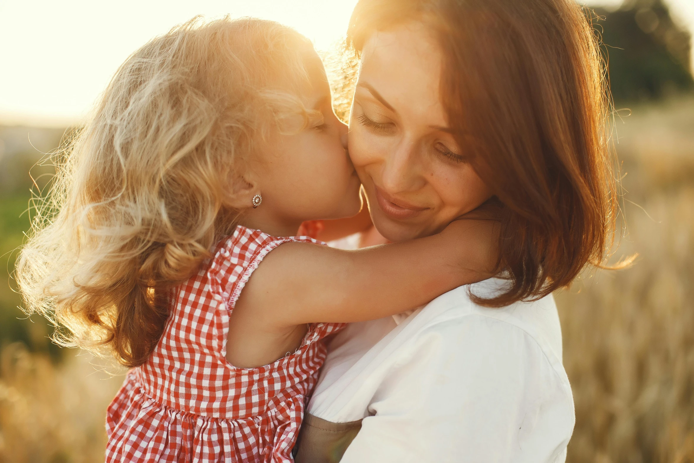 a mother and her little daughter kiss on the cheek