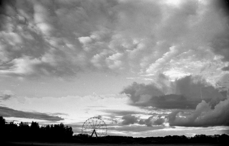 there are clouds in the sky above a ferris wheel