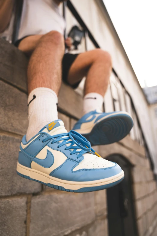 a man in blue nike sneakers hanging off a brick wall