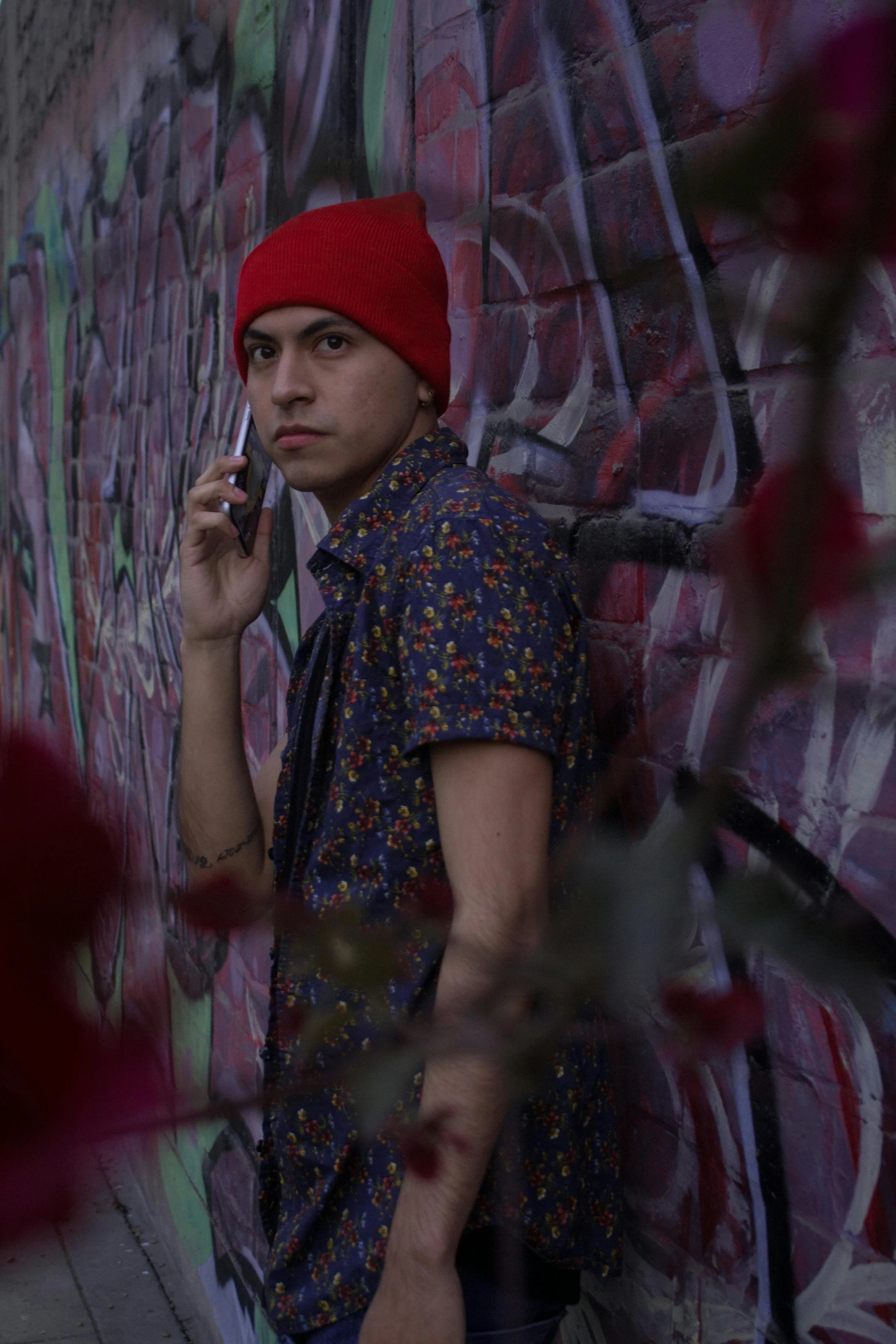 a man talking on a cell phone in front of a wall with graffiti