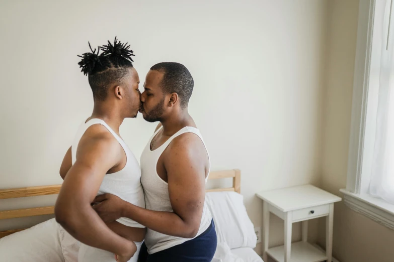 a couple kissing in bed with one laying on the other's chest