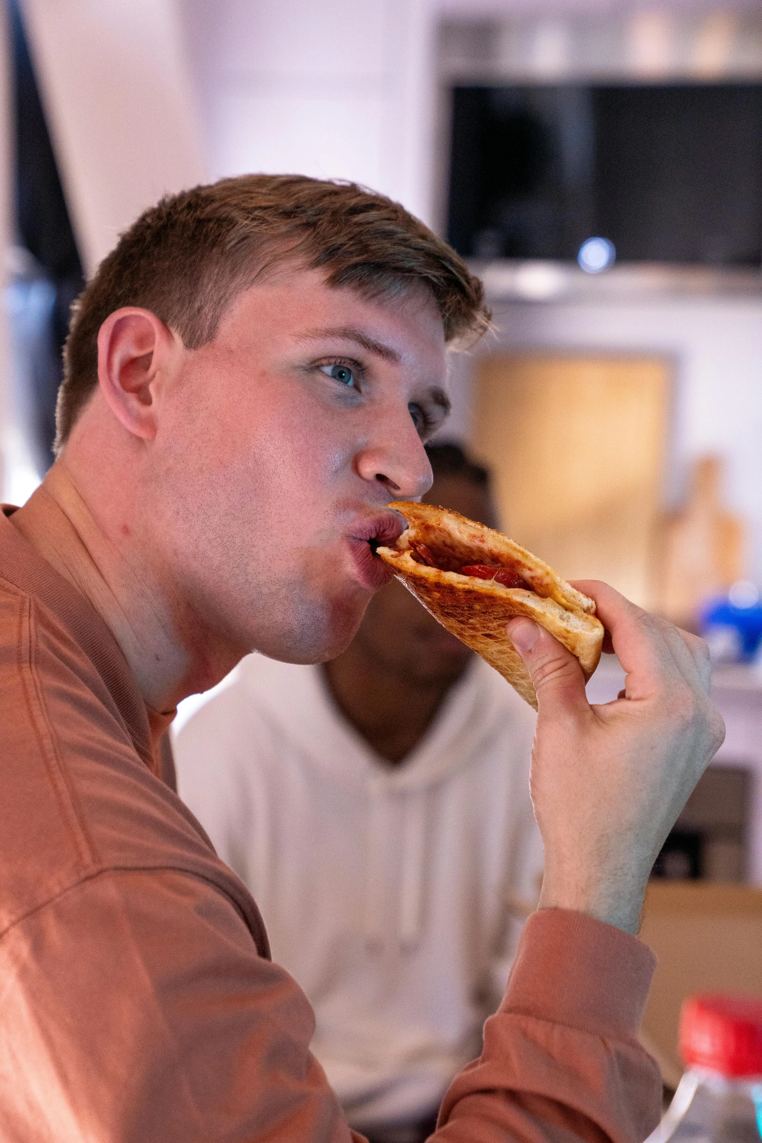 a man with brown jacket and white shirt holding a sandwich