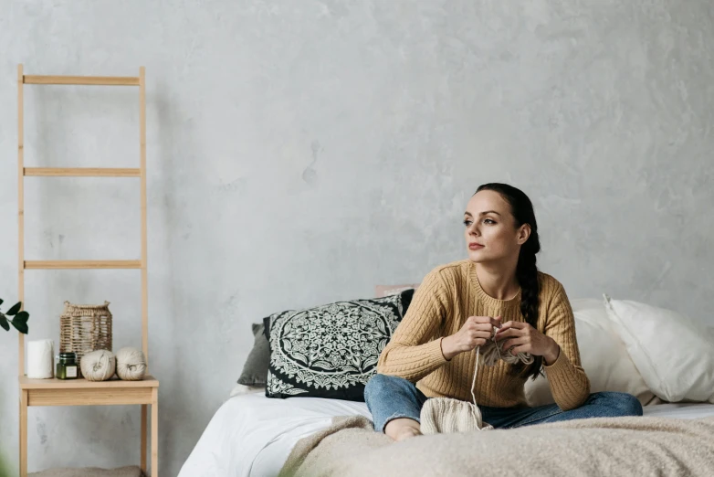 woman sitting on the bed with some knitting supplies