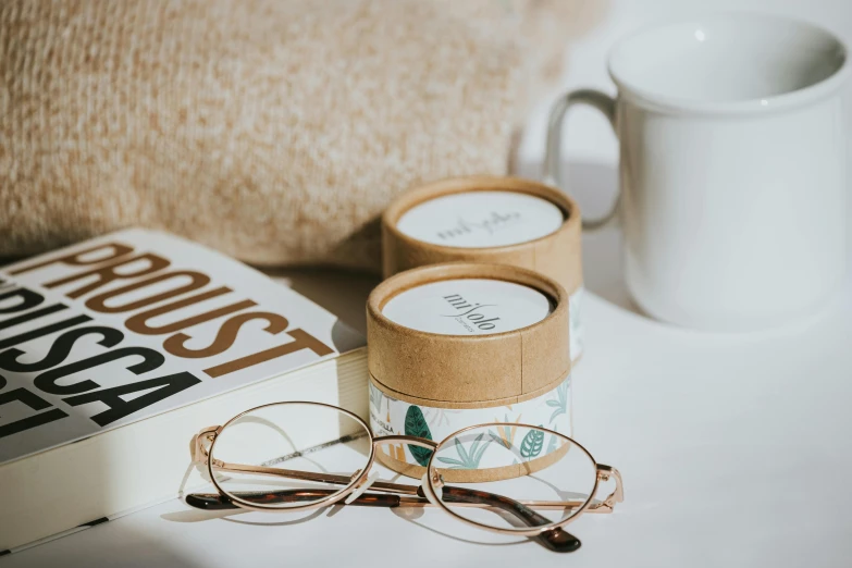 a pair of glasses sitting on top of a white table next to a book