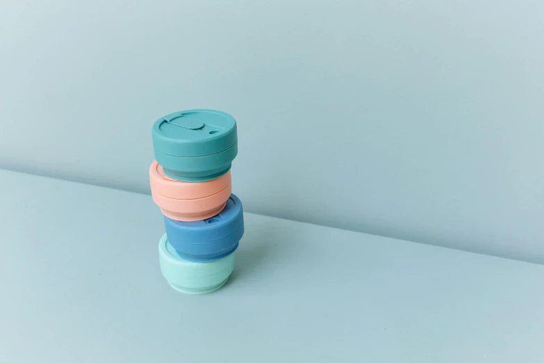 a stack of four different colored lids on a blue surface