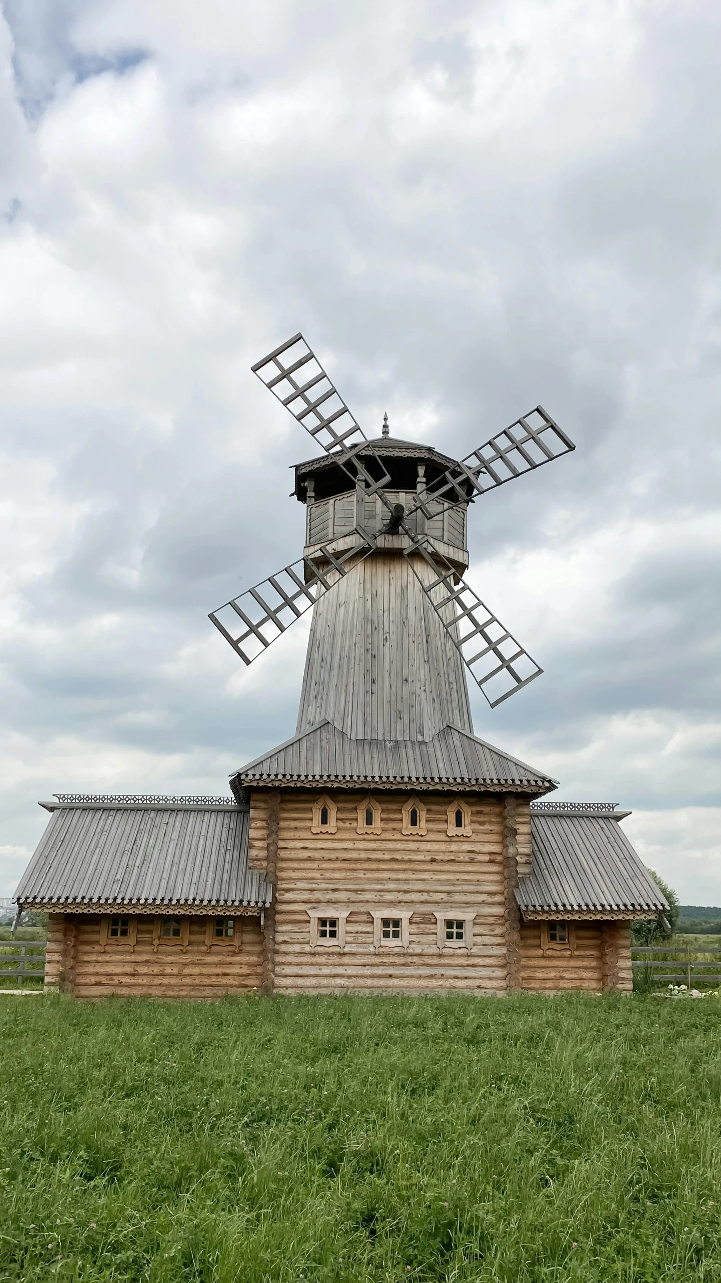 a wooden windmill sits on top of a field