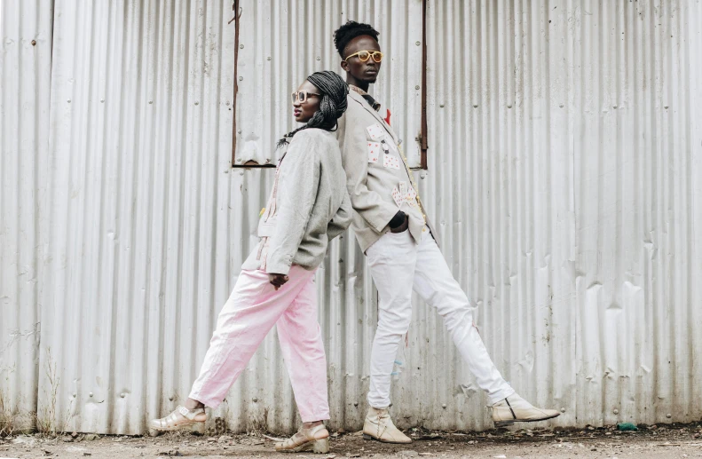 a man and woman walking together against a corrugated building