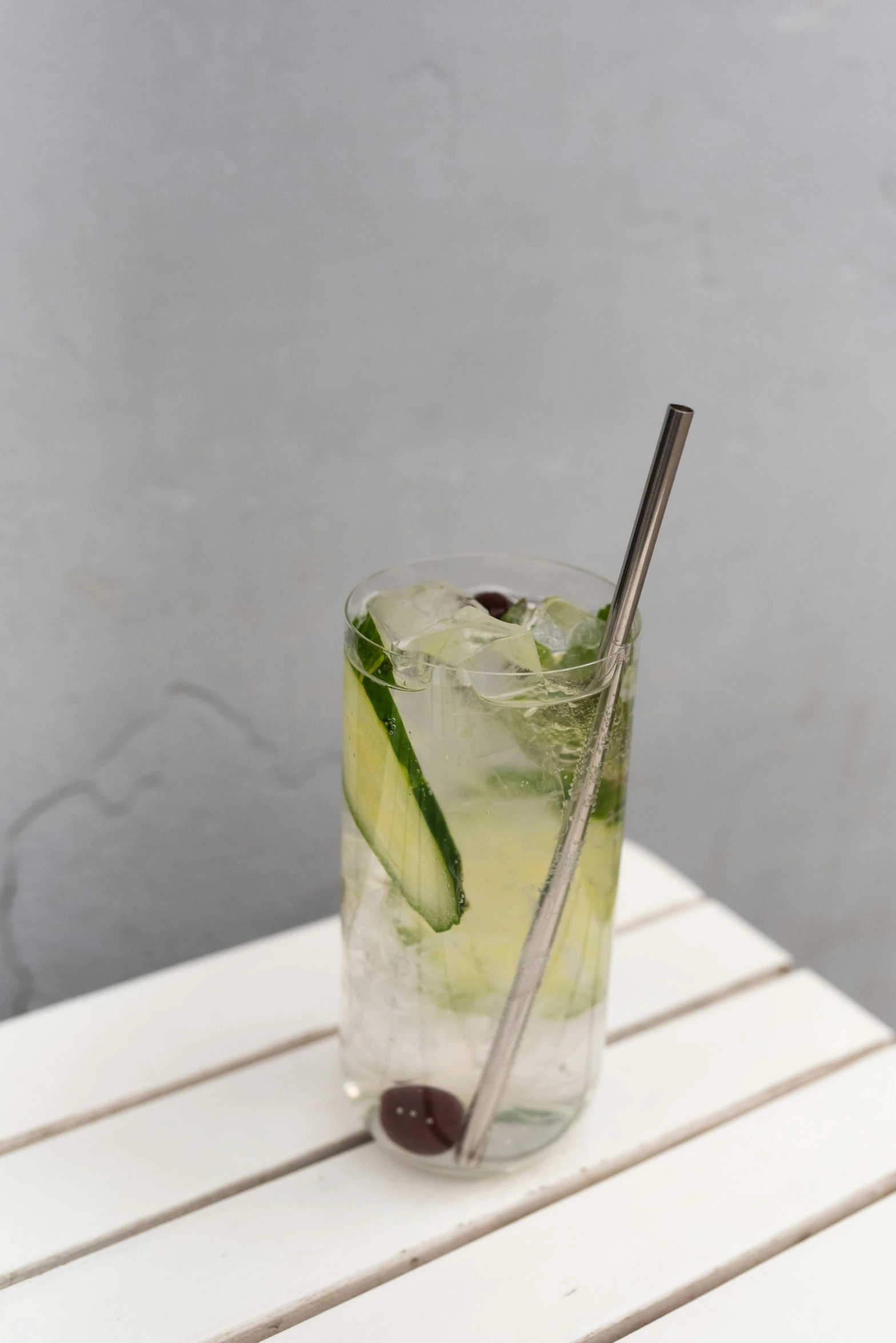 a drink with a garnish and green leaf sitting on a white table