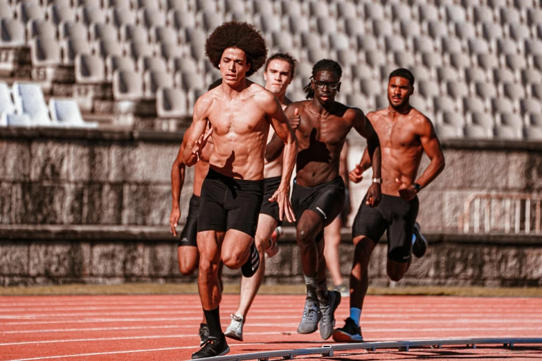 three shirtless men run on a running track