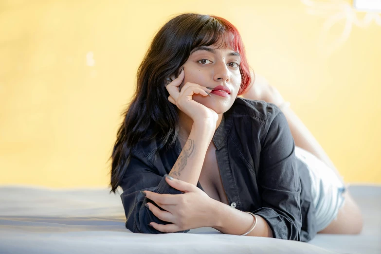 a young woman is posing on her bed with her hand to her lips