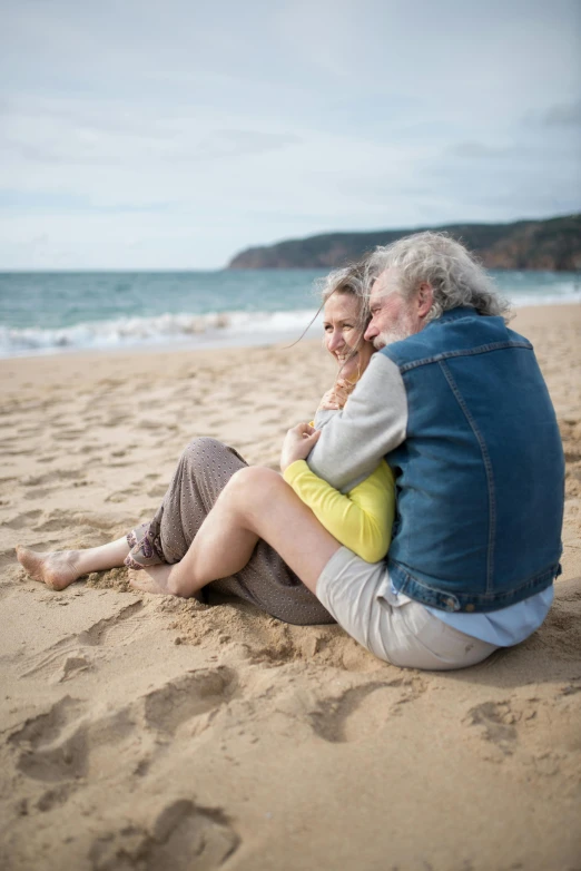 a man and woman sitting in the sand together