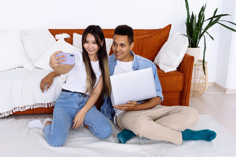 a couple holding laptops while sitting on the floor