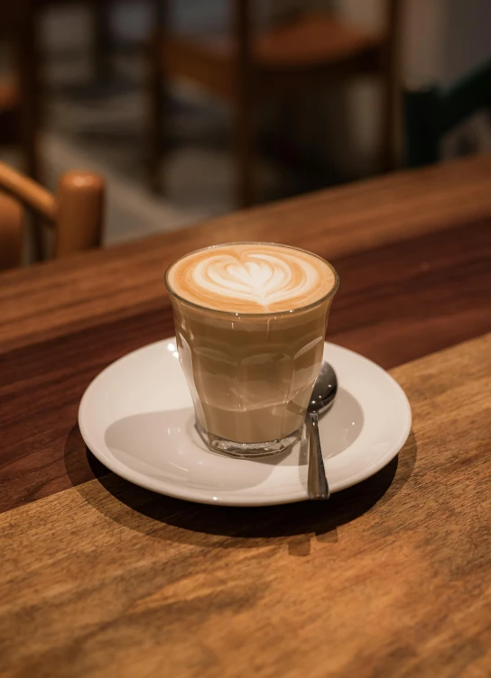 a cappuccino sitting on a wooden table in front of a chair