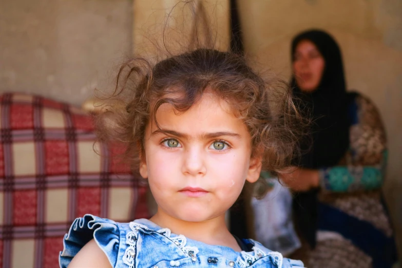 a girl with curly hair standing next to a woman