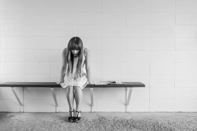 the woman is sitting down alone by her bench