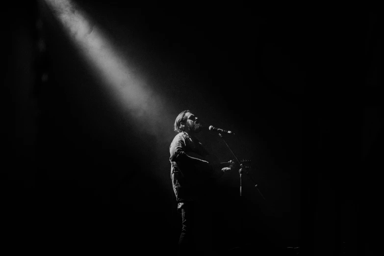 a man standing under a spotlight while holding a microphone