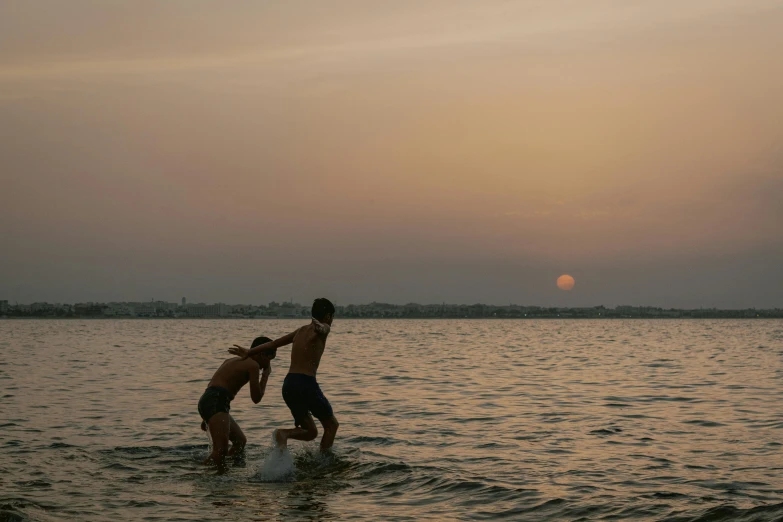 two boys are playing in the ocean with their surf board