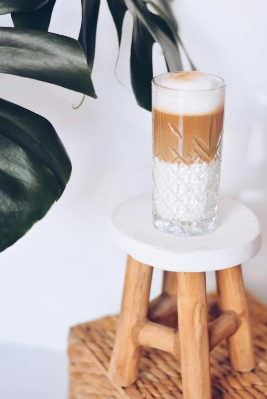 a glass sitting on a small table next to some plants