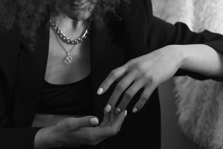 a woman with dark makeup is sitting on a couch holding her hand up