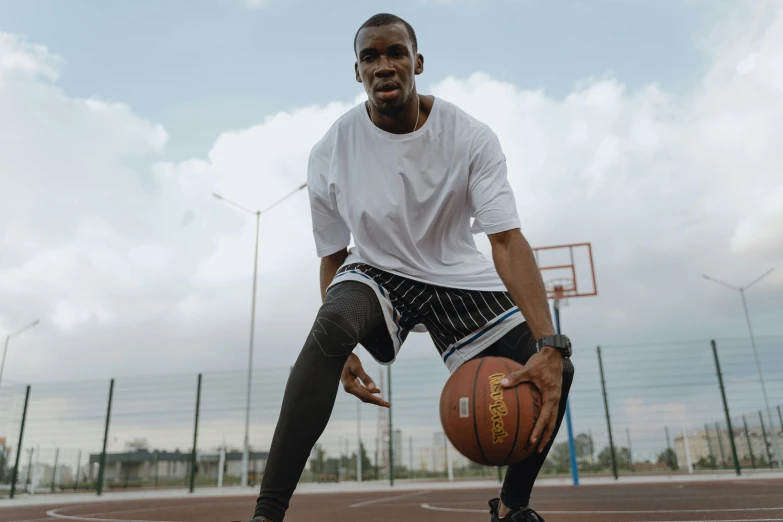 a man holding a basketball and gloves in front of an outdoor court