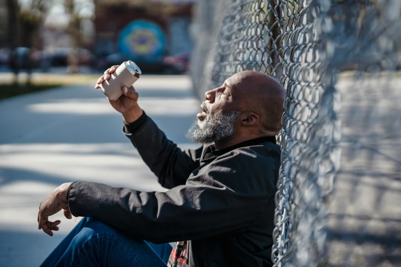 a man in black jacket holding soing up against fence