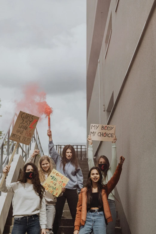 group of girls holding signs near some stairs